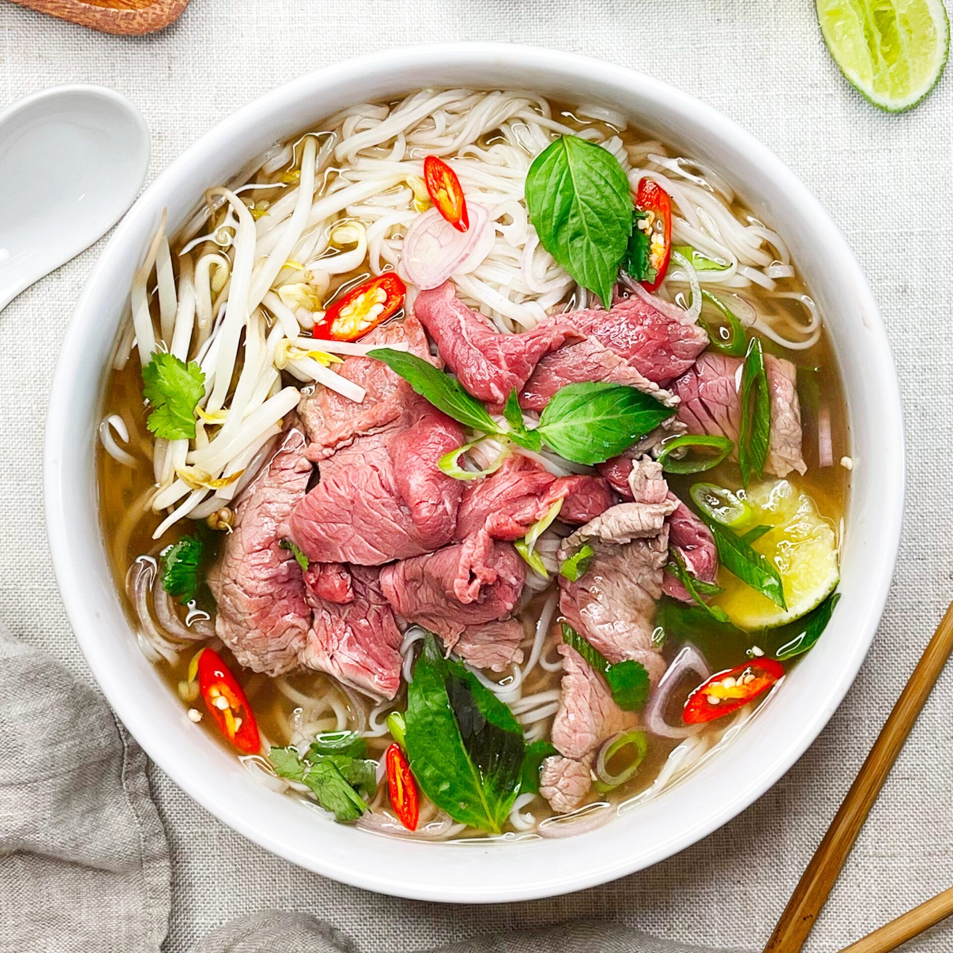 Bol de Phở fumant avec émincé de bœuf, nouilles de riz et aromates